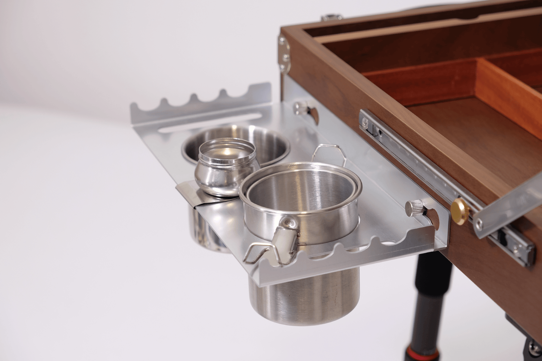 Metal cup holders attached to a wooden easel box with a white background