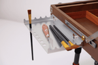 Wooden easel box with tools and a paintbrush on a white background