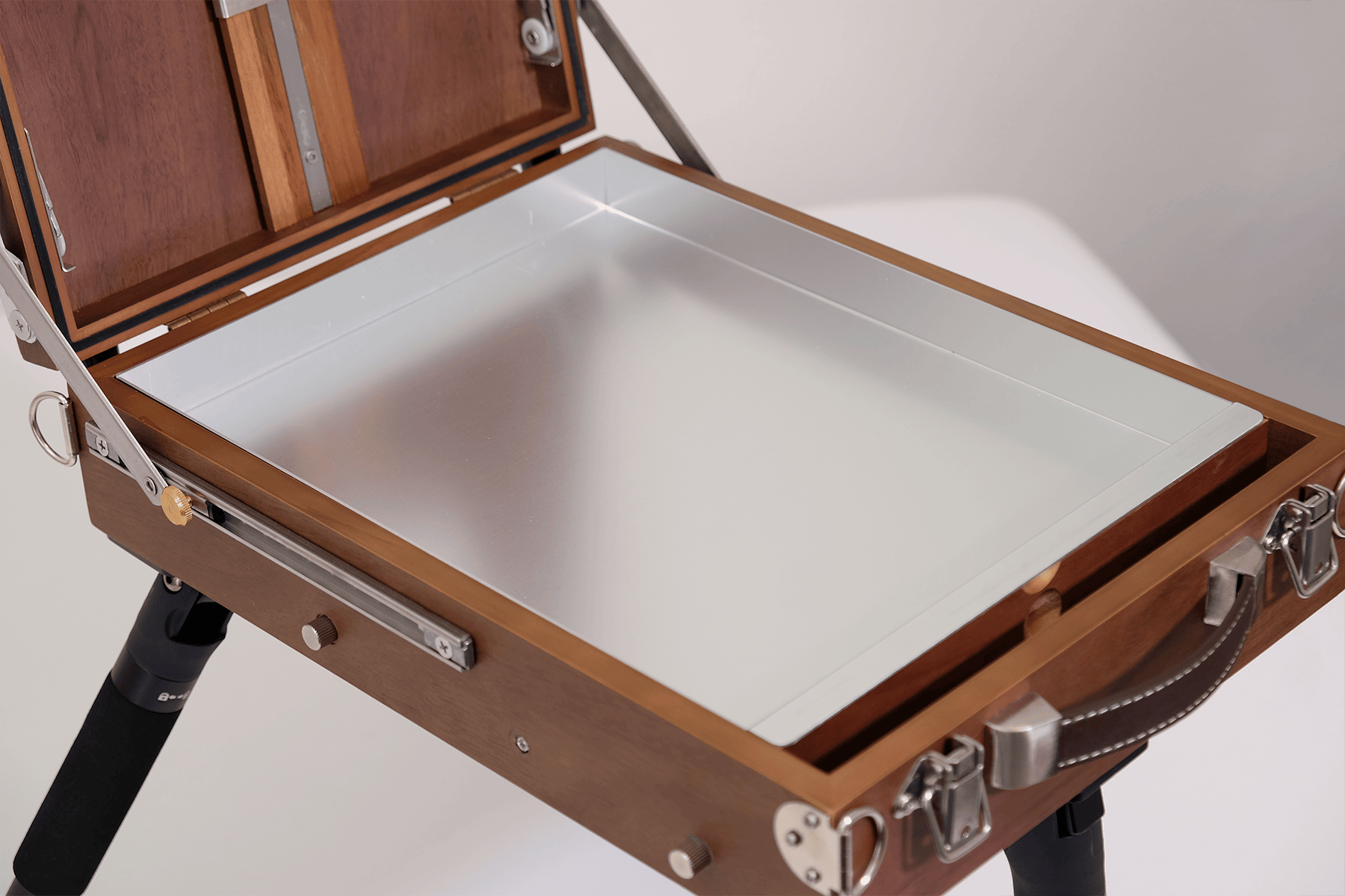 Wooden easel box opened with a metal palette on a white background